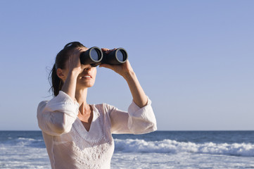 Frau mit Fernglas am Meer