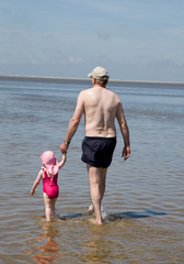 Opa und Enkelin spazieren im Watt