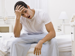 Attractive Man Sitting on His Bed and Yawning