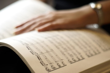 Female hand on musical score book page