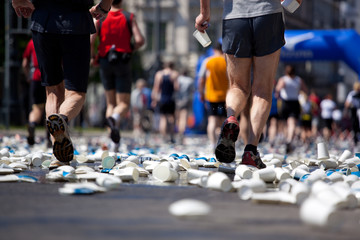 blurred marathon participants running over used paper cups