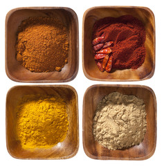 four ground up spices in wooden bowels isolated on white backgro