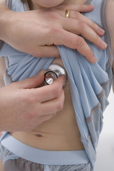 Female doctor is listening to the heartbeat of a little boy