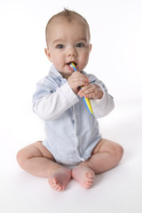 Baby boy sitting on the floor brushing his teeth