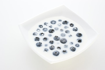 Blaubeeren mit Milch und Zucker in einer weissen Schale
