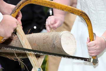 Braut und Bräutigam sägen Holz beim Hochzeitsspiel