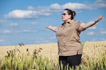 Frau breitet Arme aus im Feld (Yoga)