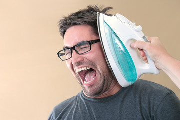 Young ethnic male is being hit with an iron.