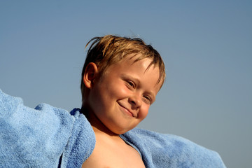 Kind lächelt zufrieden über beide Ohren am Strand, glücklich