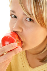 Portrait of young blonde woman eating fresh tomato
