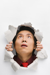 Man looking up surprisingly from hole in wall
