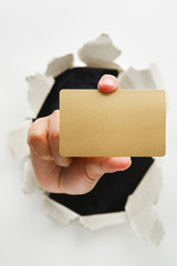 Hand breakthrough wall holding empty golden card