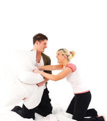 Couple having a pillow fight in bed