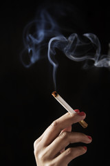 female fingers holding burning cigarette