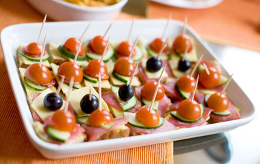 Small canapes with ham, cheese, cucumbers, tomatoes and olives
