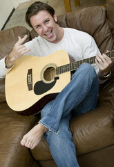 An attractive man playing the acoustic guitar