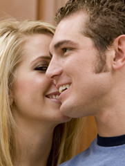 A beautiful woman whispering into her boyfriends ear