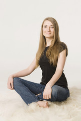 young girl a blonde with long hairs    sits on a fur bedspread