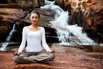 Fototapeta na wymiar Woman doing zen exercise near a waterfall