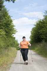 XXL-Model übergewichtige Frau beim Nordic Walking