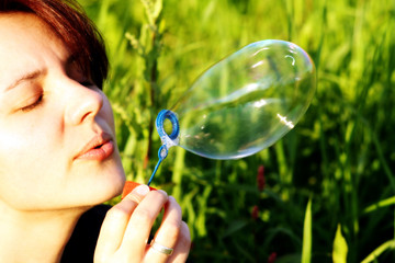 A woman is blowing a  bubble