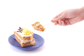 Hand with spoon snap off a peace of cake isolated on white