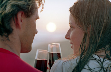 romantic couple with goblet of red wine on a beach