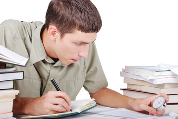 Young man writting on desk with books