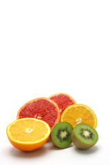 Pamplemousse, kiwi et orange coupés en deux sur fond blanc