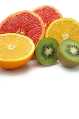 Pamplemousse, kiwi et orange coupés en deux sur fond blanc