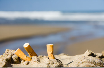 three cigarettes on beach - 15627804