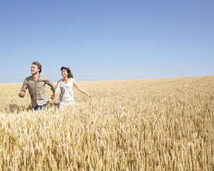 Naklejka na ściany i meble couple running in wheat field