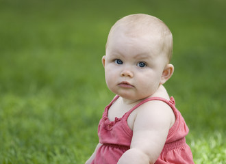 Baby girl looking at you from grass