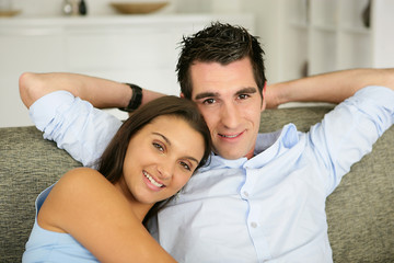 Jeune couple souriants assis sur un canapé