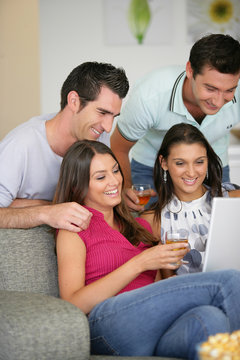 Groupe d'amis devant un ordinateur portable avec un verre de vin