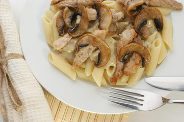 Pasta with mushroom and meat on a white plate
