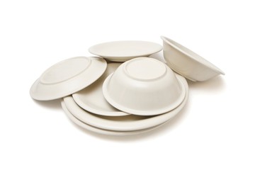 Pile of beige dinner plates, soup plates and saucers isolated