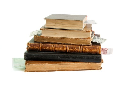 Stack of old books with banknote bookmarks isolated