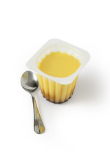 Flan au caramel et cuillère sur fond blanc