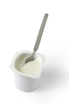 Cuillère dans un yaourt nature sur fond blanc
