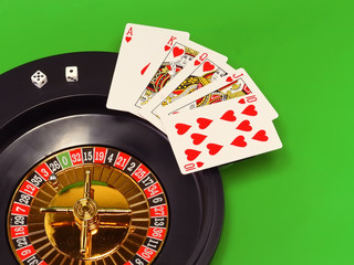 The casino roulette and playing cards on green broadcloth.