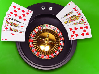 The casino roulette and playing cards on green