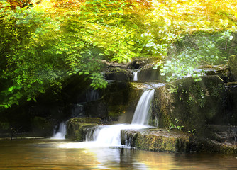 Atmospheric Autumn Waterfall with light bursts in the Forest