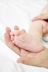 Woman hand holds baby leg