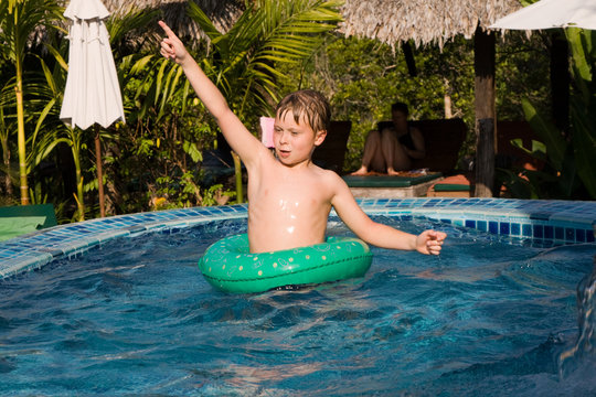 Kind gestikuliert voller Freude in einem Schwimmreifen im Pool