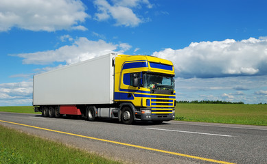 Fototapeta na wymiar Pojedynczy ciężarówka z niebiesko-żółtym kabiny w ruchu na autostradzie.