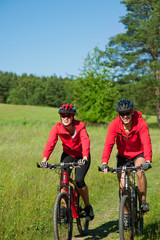 Plakat Young man and woman cycling in the nature