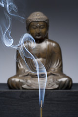 Bronze statue of Buddha with burning incense