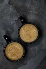 double espresso coffee in black cups on black stone background