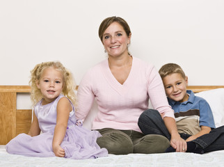 Mother and Children Sitting on Bed